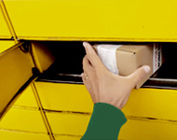 Ręka wkładająca pudełko kartonowe do skrytki paczkomatu